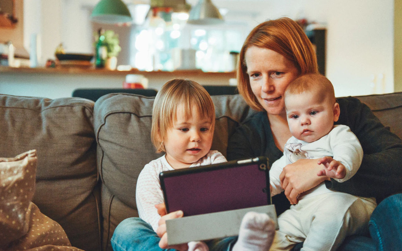 A lady sitting with her children looking at a computer.